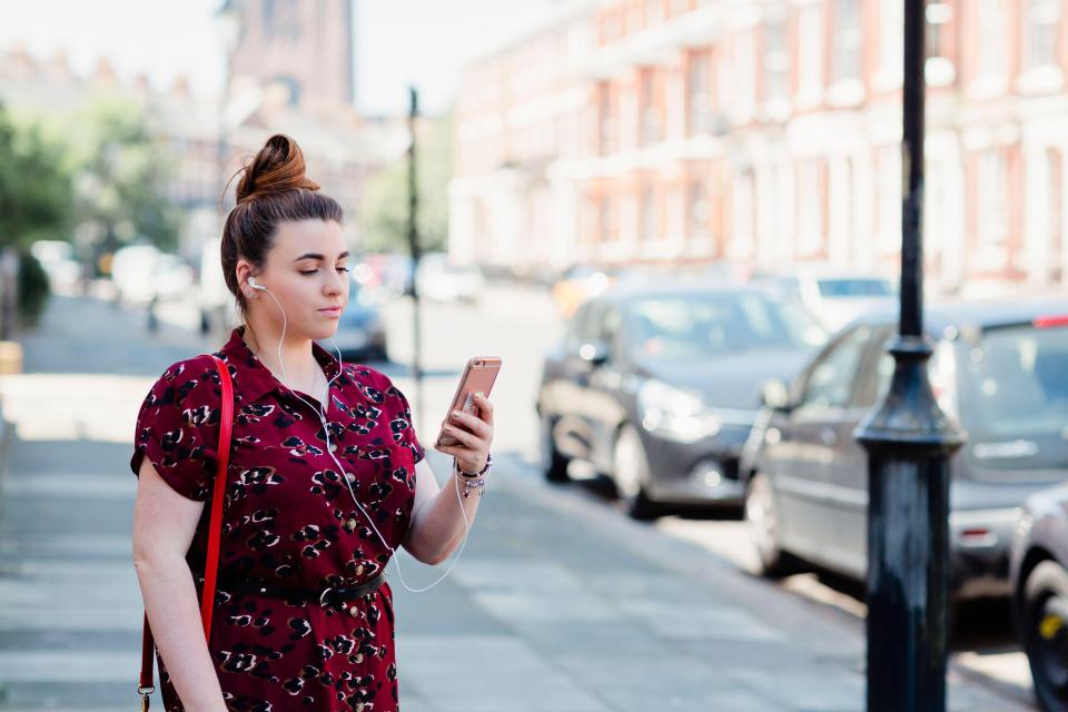 Woman using smartphone while listening to earphones.