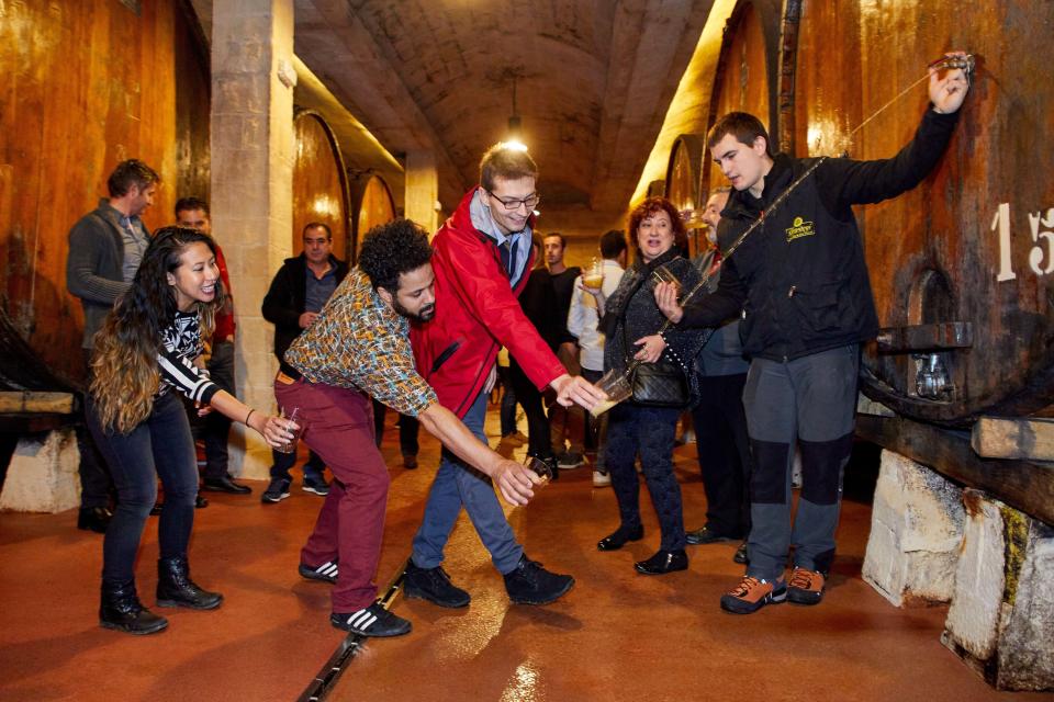 Tourists on a guided tour of a cider house in the Basque Country, Spain.