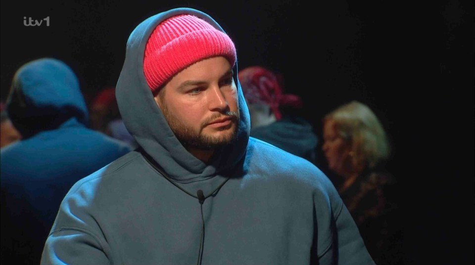 Housemate in a pink beanie and blue hoodie during a face-to-face nomination.