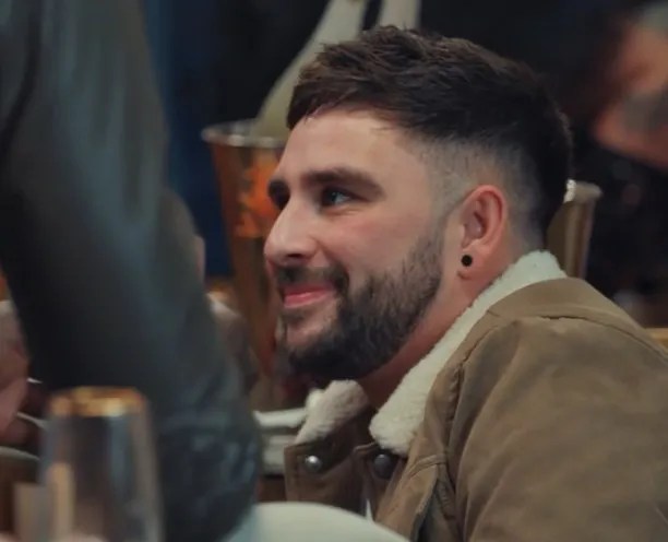 Man smiling in a brown jacket.