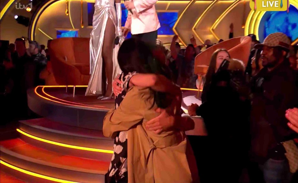 A winner of a reality show embraces loved ones on stage.
