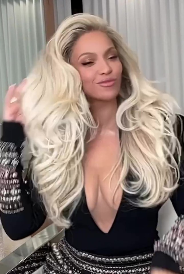 Beyoncé in a black, low-cut outfit, showing off long blonde hair.