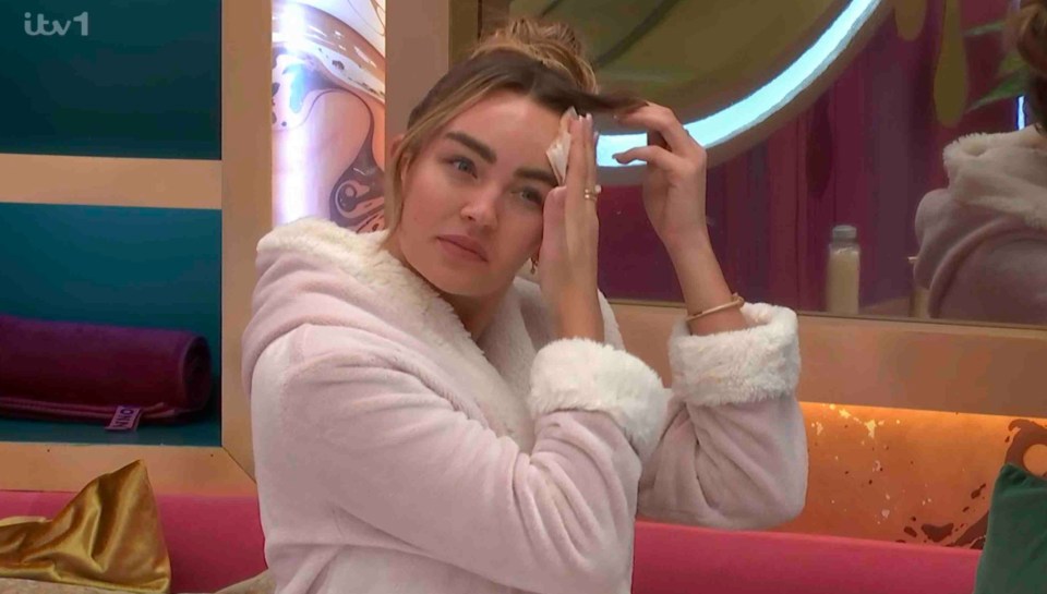 Ella Rae Wise in a pink robe, touching her face.