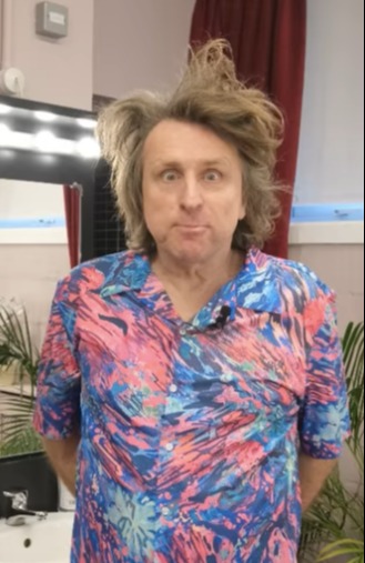 Man with messy hair wearing a patterned shirt.