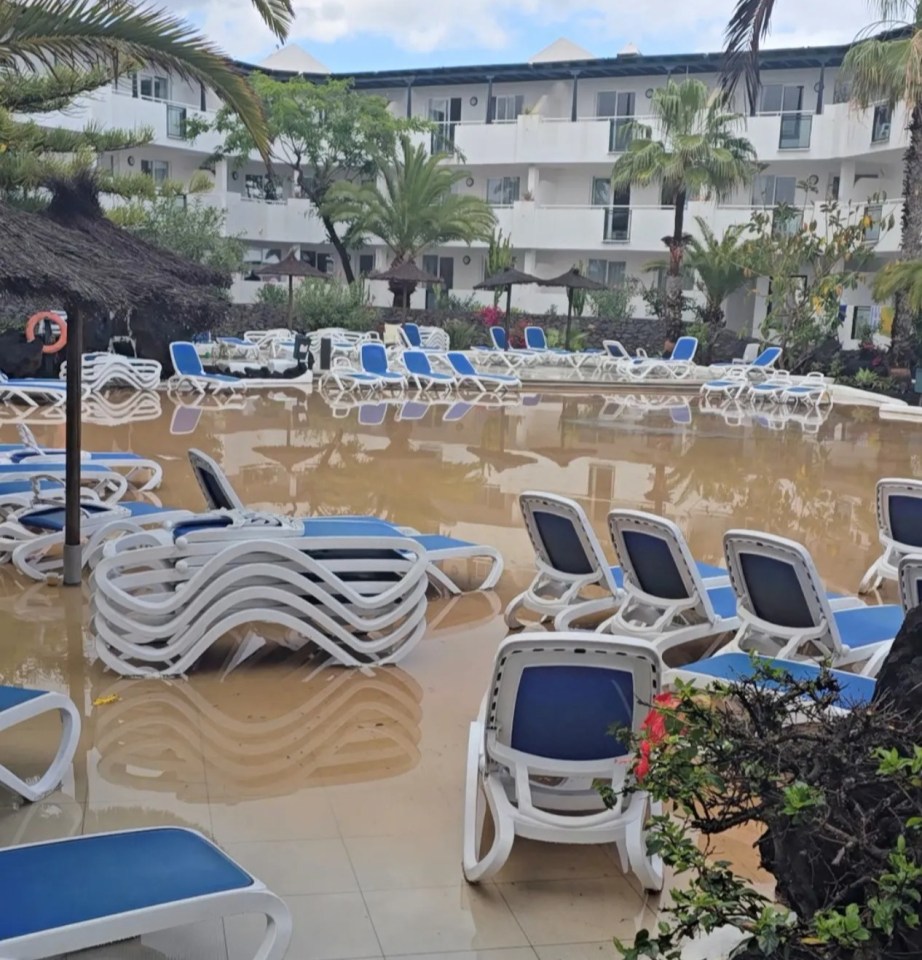Flooded pool area with submerged lounge chairs.