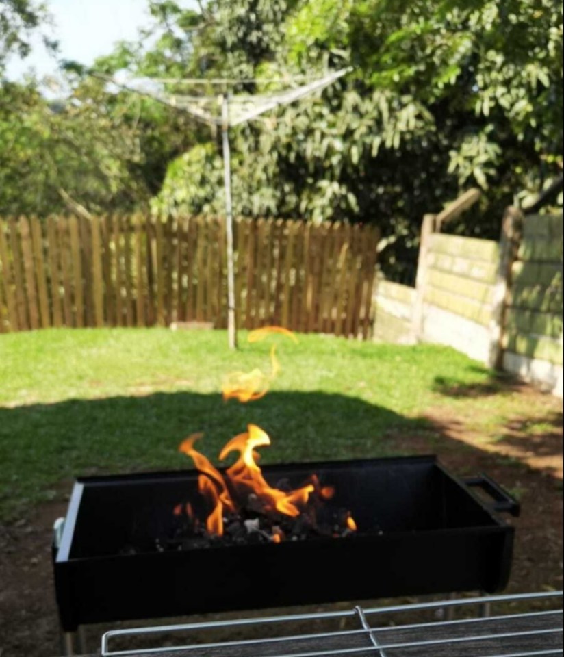 Braai with flames burning in a backyard.