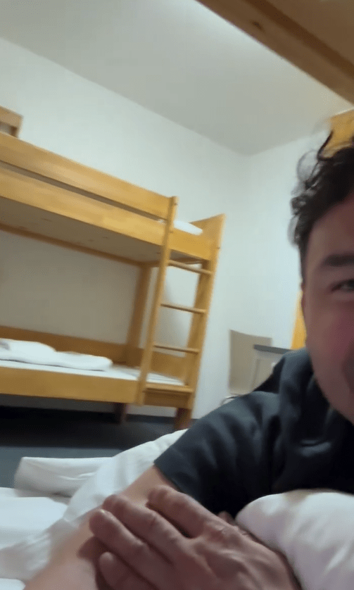 Person lying in bed in a room with bunk beds.