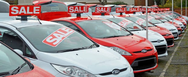 D2GRYM Used Ford cars on sale dealership forecourt outside showroom arranged alternate red and white obscured numberplates