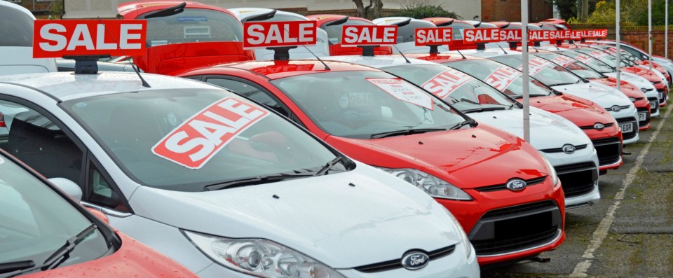 D2GRYM Used Ford cars on sale dealership forecourt outside showroom arranged alternate red and white obscured numberplates