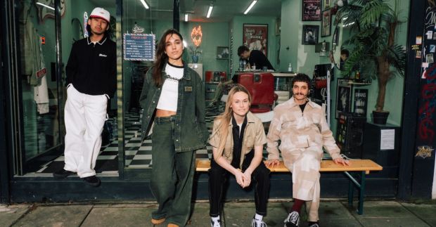 Four young adults in Dickies clothing pose outside a barbershop.