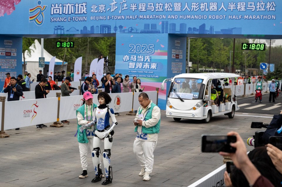 BEIJING, CHINA - APRIL 19: A female Humanoid robot is assisted by support technicians as it starts the Beijing E-Town Humanoid Robot Half Marathon on April 19, 2025 in Beijing, China. According to organizers, the event was the first of its kind and featured twenty-one humanoid robot runners. (Photo by Kevin Frayer/Getty Images)