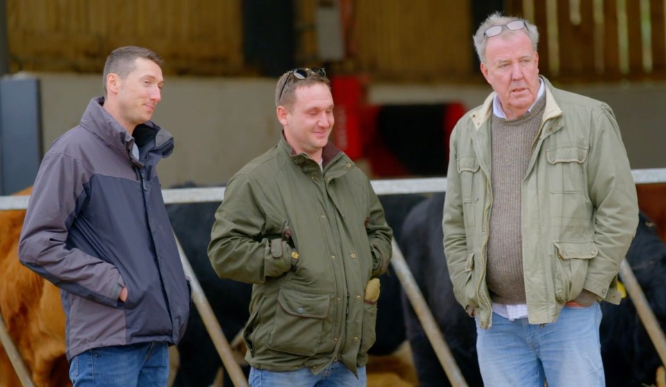 Three men standing in a barn.