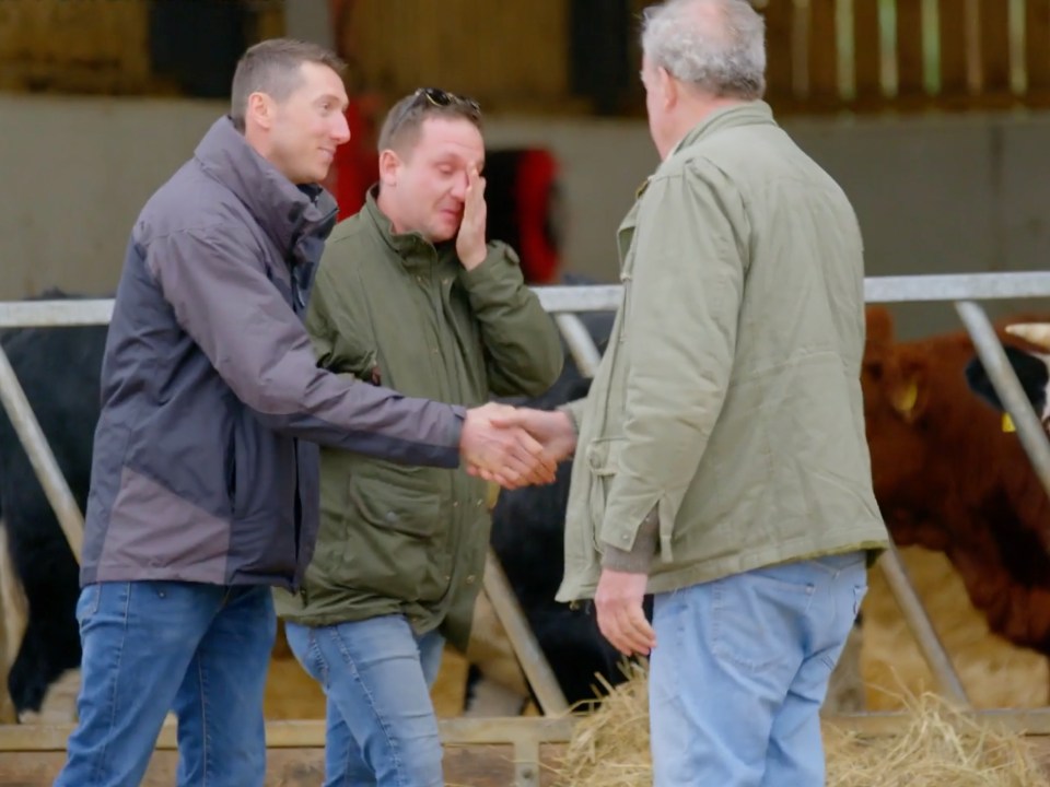 Three men shaking hands in a barn.