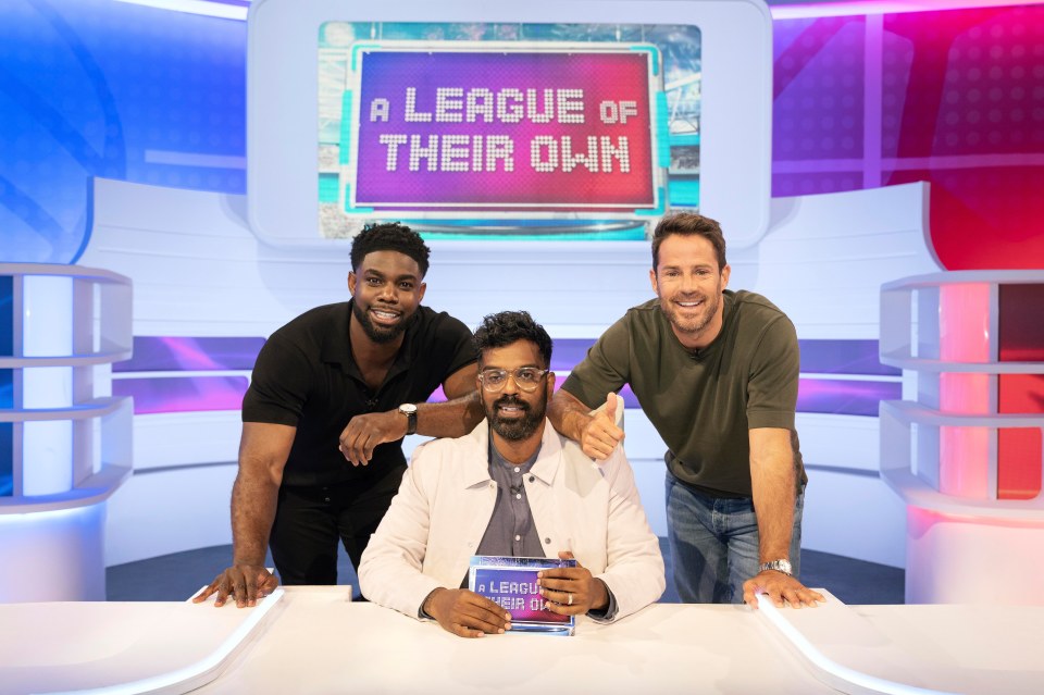 Three men on a game show set, holding a "A League of Their Own" sign.