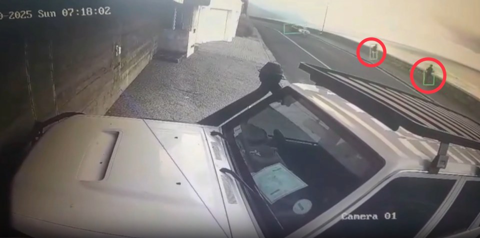 Security camera footage of a vehicle with two people visible in the distance.