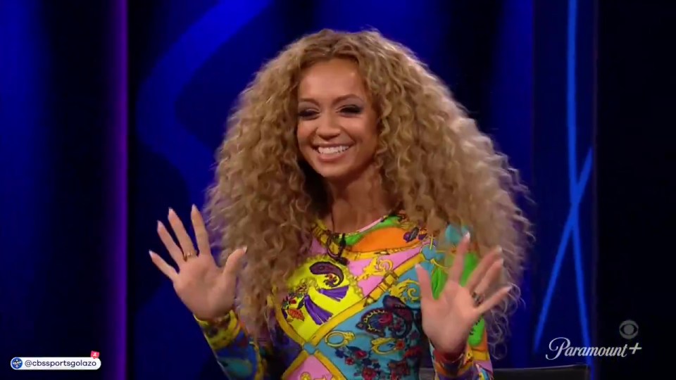 Woman with long curly hair waving.