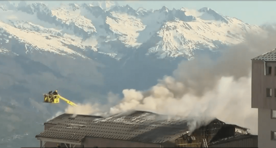 Firefighters battling a building fire in a snowy mountain resort.