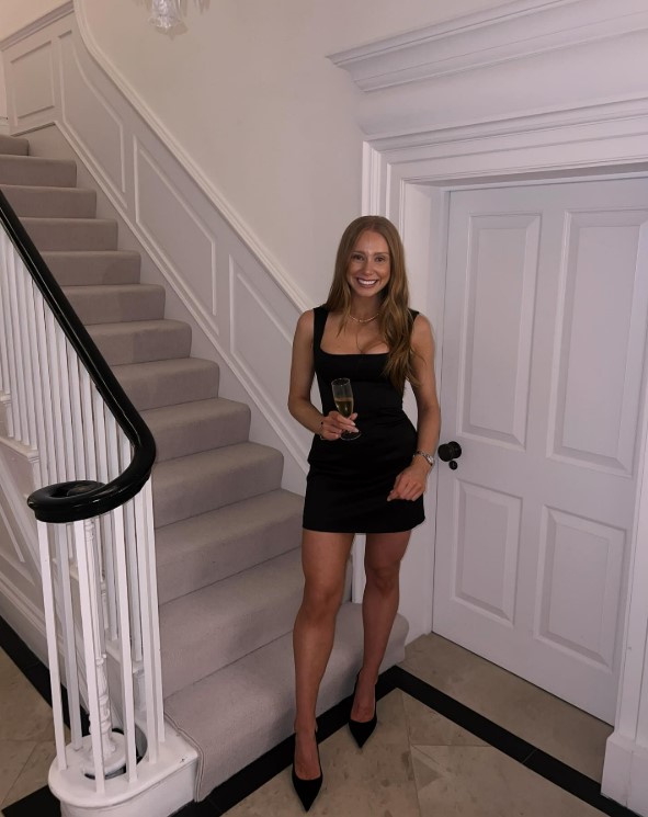 Woman in black dress holding champagne flute.