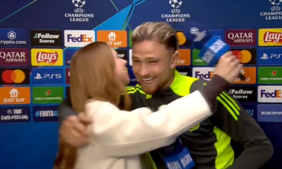 A woman hugging a soccer player during a post-game interview.