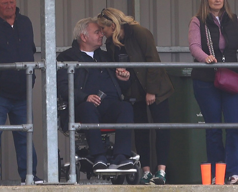 A woman leans down to kiss a man in a wheelchair.