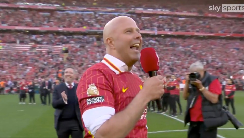 Man in Liverpool jersey speaking into a microphone at a stadium.