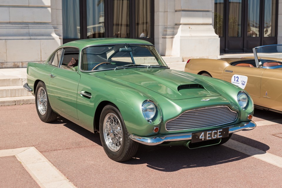 Green Aston Martin DB4 parked outdoors.