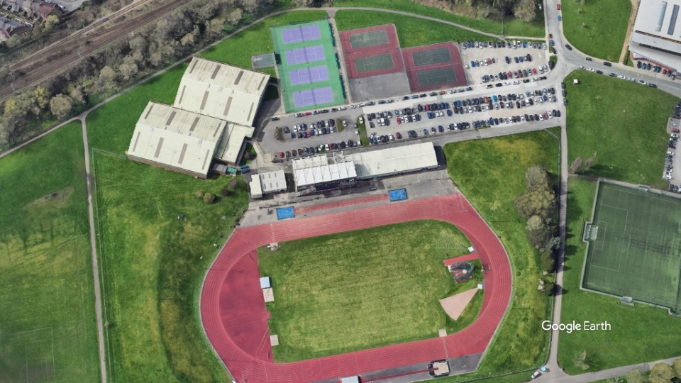 Aerial view of a sports complex with a running track, tennis courts, and soccer field.