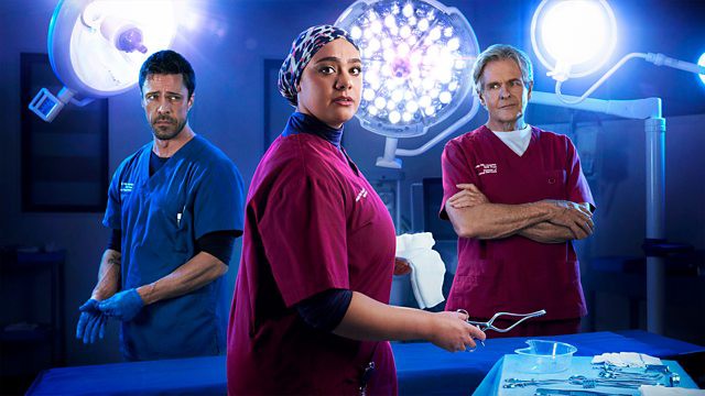 Promotional image for the BBC series Casualty, showing three doctors in scrubs.
