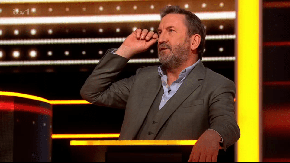 Man in suit on game show set.