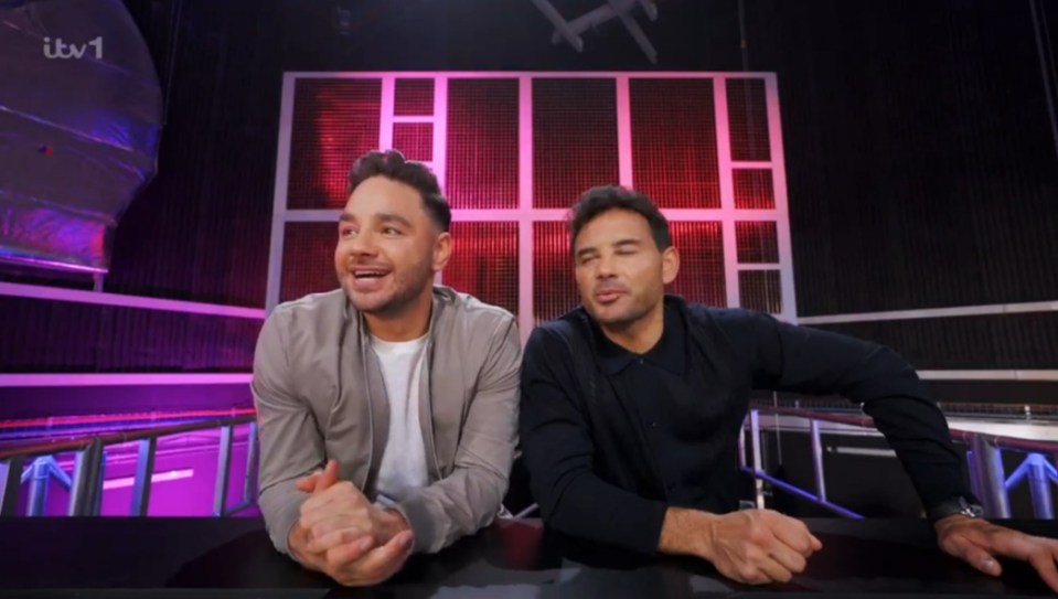 Screenshot of two men sitting at a table.