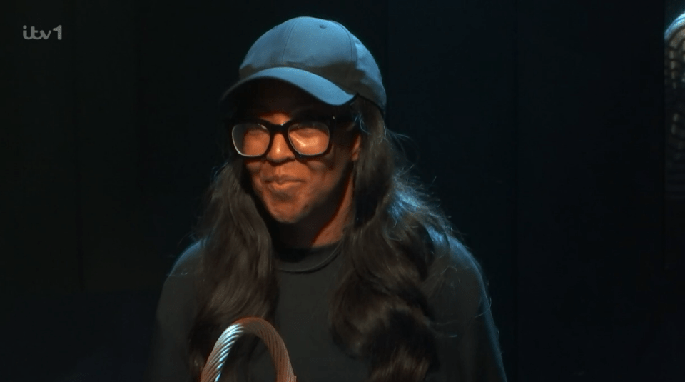 Screenshot of a woman wearing glasses and a baseball cap.