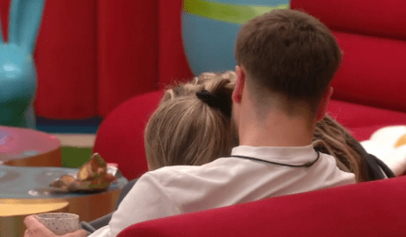 Screenshot of a couple cuddling on a red couch.