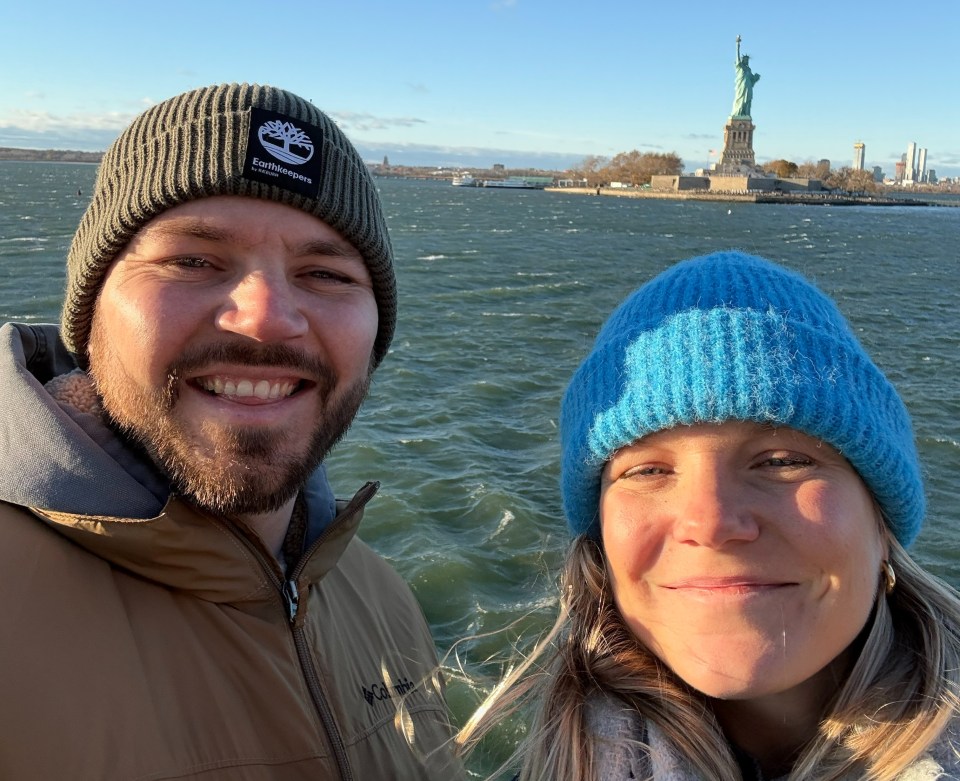 Couple on a ferry in New York, with the Statue of Liberty in the background.