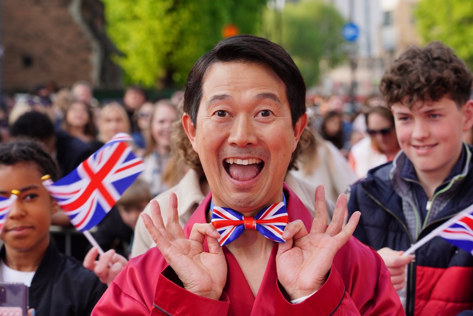 Akira, wearing a red robe and Union Jack bow tie, at a Britain's Got Talent photo call.