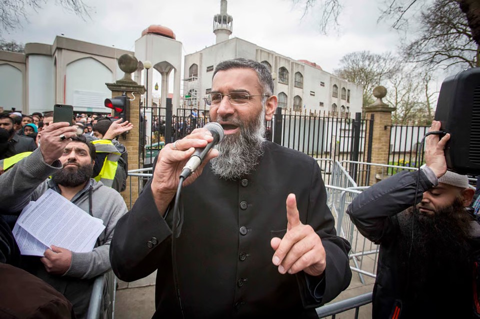 Anjem Choudary speaking into a microphone outside a mosque, urging Muslims to abstain from voting.