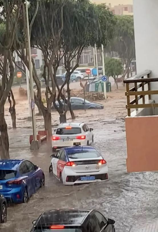 Cars submerged in floodwaters on a street.