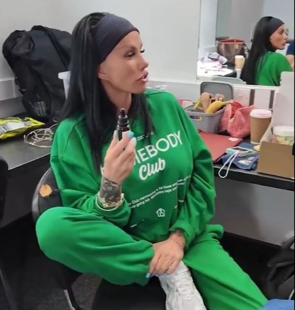 Katie Price holding a small bottle while sitting.