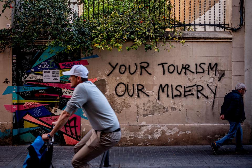Graffiti reading "Your Tourism, Our Misery" on a wall in Barcelona.