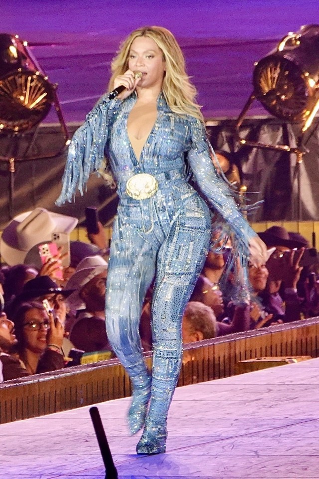 Beyoncé performing on stage in a sequined denim jumpsuit.