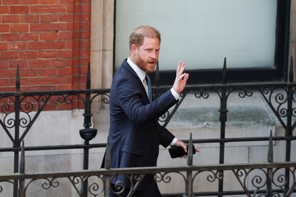 Prince Harry waving as he walks past a fence outside the High Court in London.