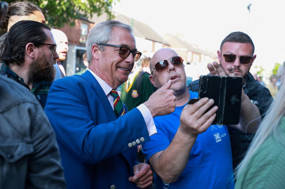 Nigel Farage with a man looking at a phone.