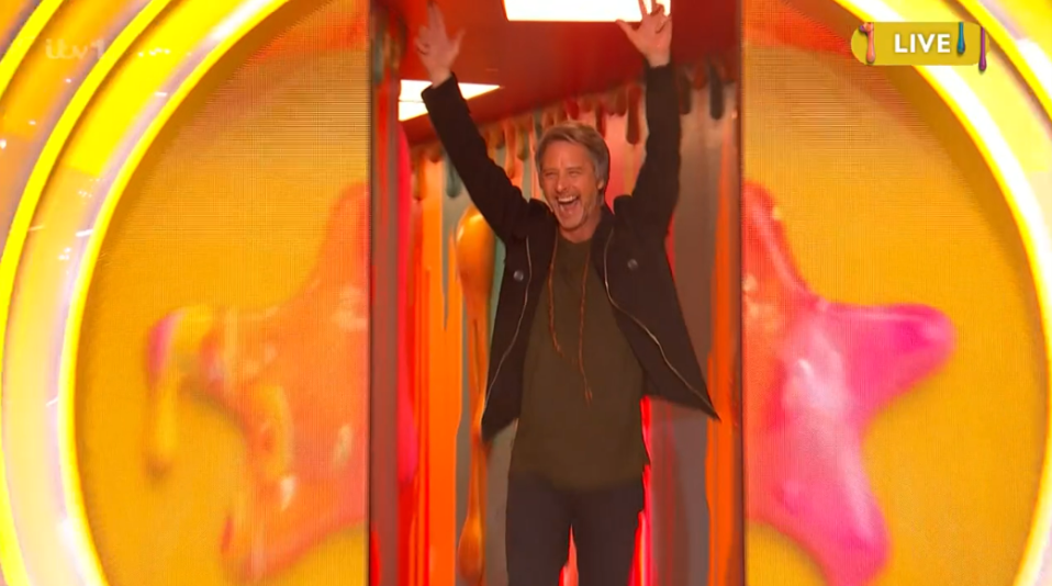 Chesney exiting a colorful tunnel with his arms raised.