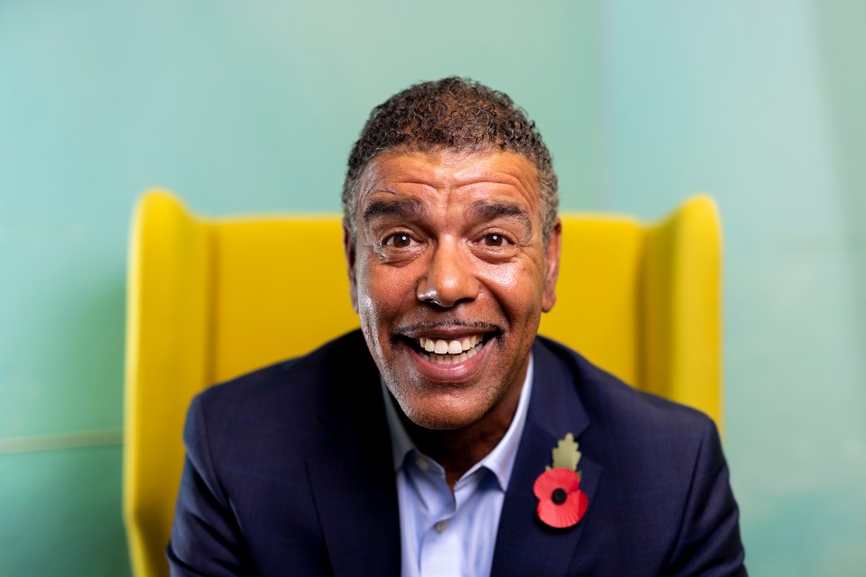 Chris Kamara, smiling, wearing a suit and poppy.
