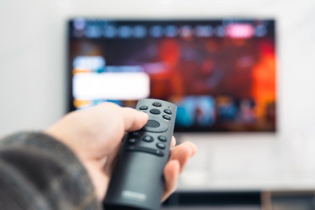 Close-up of a person holding a TV remote.