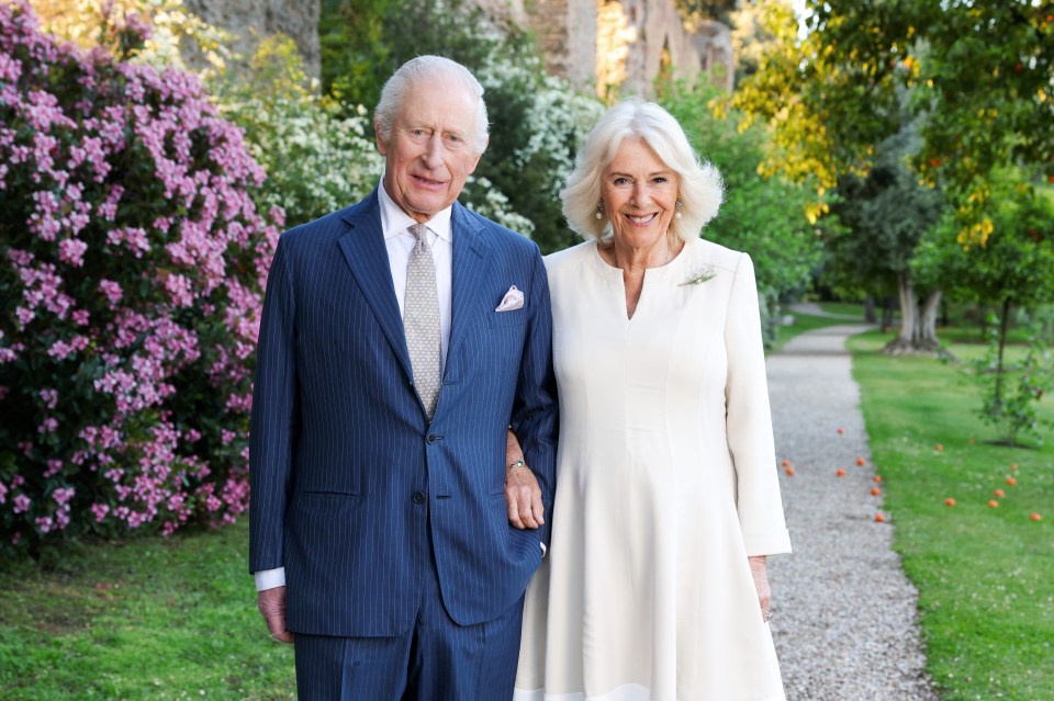 Portrait of King Charles III and Queen Camilla in a garden.