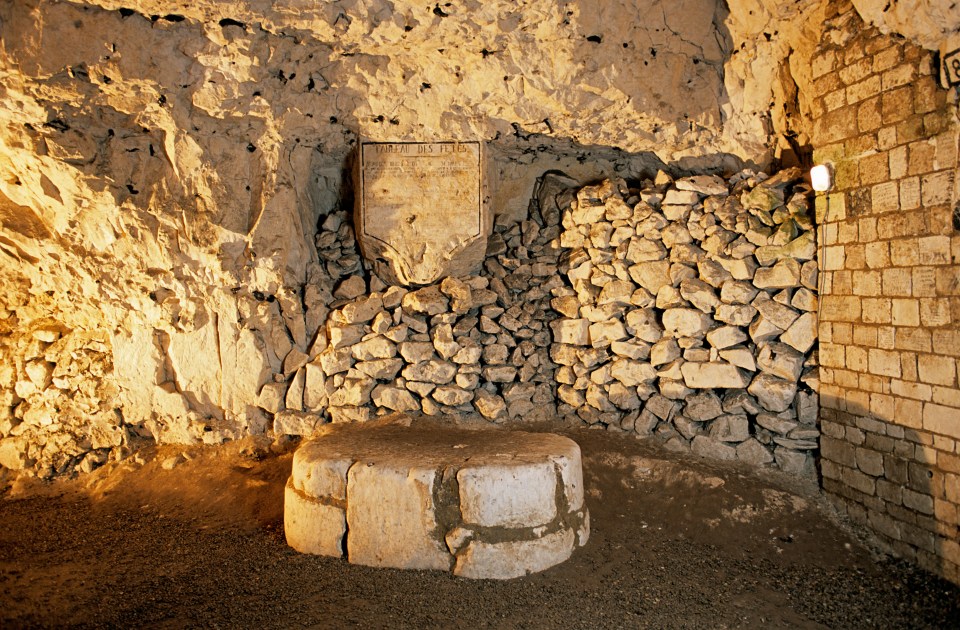 Stone table in a Naours grotto with a stone wall and plaque.