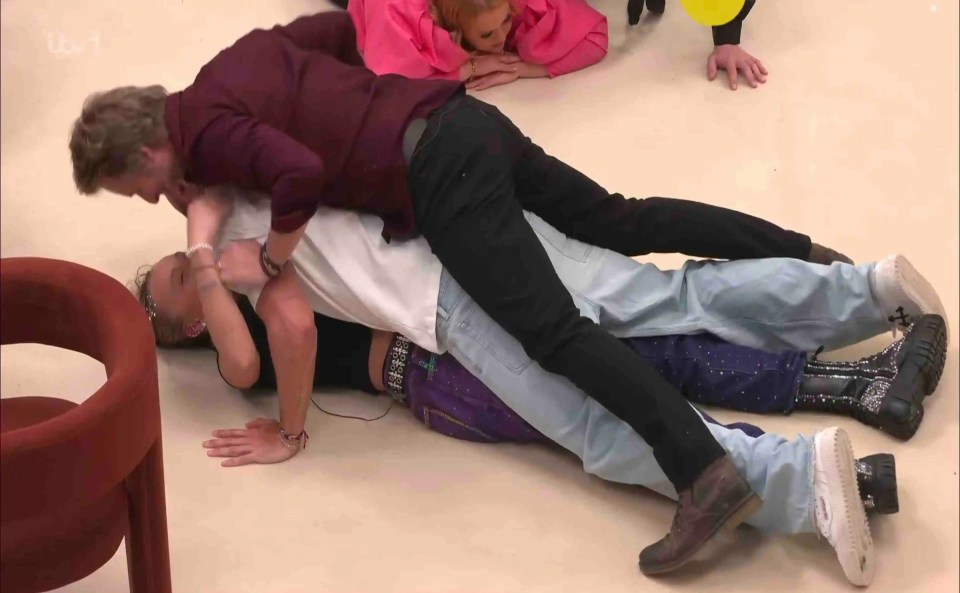Three people on the floor, piled on top of each other.