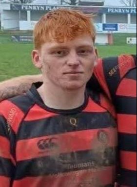 Portrait of a young man with red hair wearing a rugby jersey.