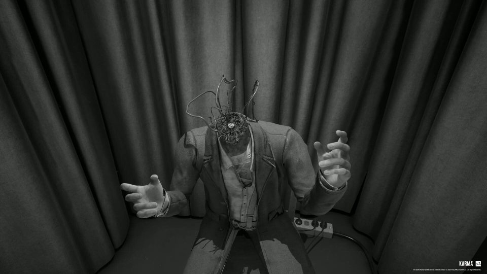 KARMA: The Dark World game screenshot; a figure with wires where its head should be, sitting before dark curtains.