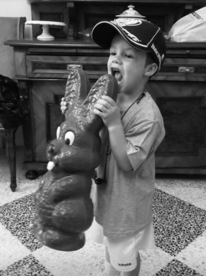 Black and white photo of a young boy holding a large chocolate bunny.